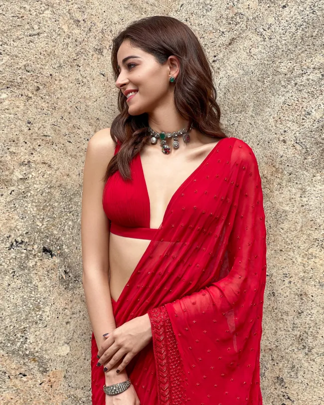 red sleeveless blouse underneath her saree with trapeze neckline